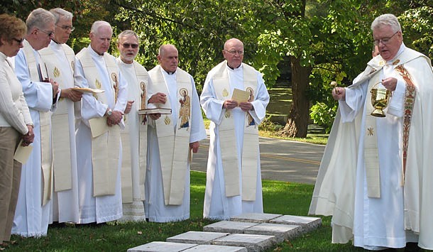 Paulist president Father John F. Duffy sprinkles holy water on the new graves of 70 of his Paulist brothers.
