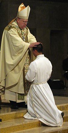 Auxiliary Bishop Francisco Gonzalez Valer, SF, of the Archdiocese of Washington, D.C., lays hands on Dat Q. Tran, CSP, as Mr. Tran is ordained a transitional deacon.