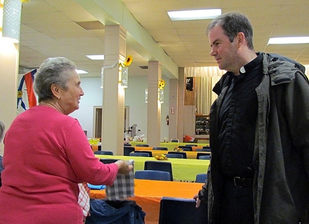 Father Thomas Gibbons, CSP, stops by the Italian food table for a chat during the annual Fall Fair at St. Peter Church in Tornto. 