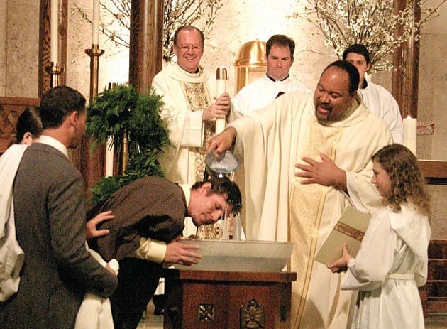 Father Steven Bell, CSP, baptizes a man during the Easter Vigil at St. Austin Church in Austin, Texas, during the Liturgy of Initiation.