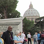 Santa Susanna parishioner and tour guide Laila Volpe tells a group of pilgrims about the treasures inside the Vatican Museum on the building's porch, which boasts a great view of St. Peter's dome.