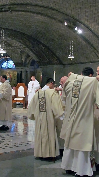 After his official ordiantion to the diaconate, Jimmy Hsu, CSP, is vested with the stole and dalmactic by Father John Behnke, CSP. (They stand to the left.)