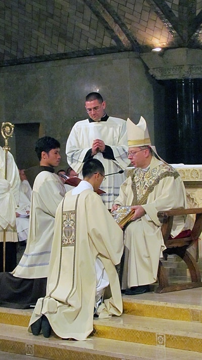 Bishop Barry C. Knestout of Washington, D.C., presents Paulist Jimmy Hsu with the Book of Gospels.
