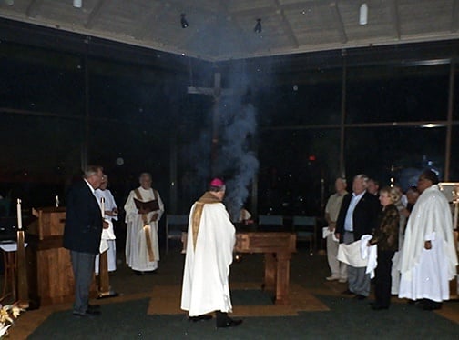 In a darkened church, Bishop Joe S. Vásquez incenses the new altar at St. Paul the Apostle Parish in Horseshoe Bay, Texas.