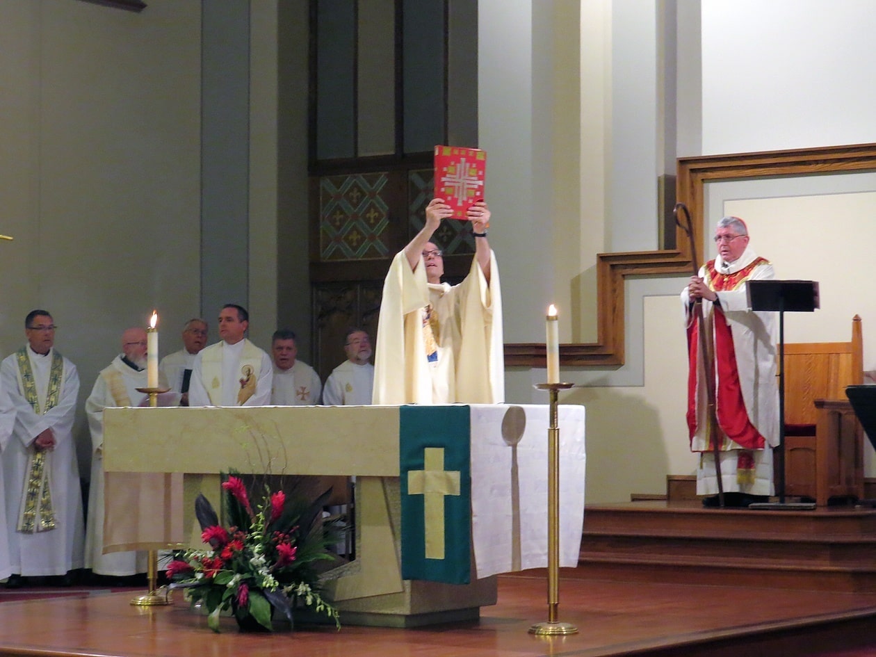 Paulist President Father Eric Andrews holds up the Book of Gospels.