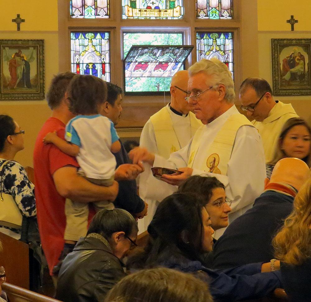 Father John F. Duffy, CSP, distributes Communion.
