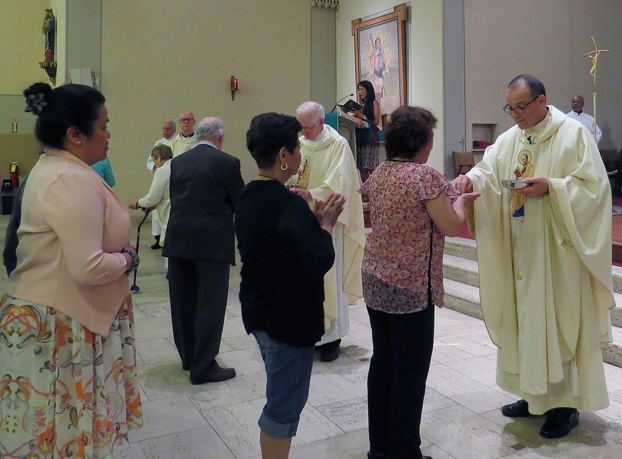 Father Eric Andrews, Paulist president (far right), distributes the Body of Christ.    